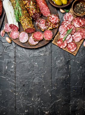 Baharat ve otlar ile farklı salam ürün yelpazesine. Rustik siyah arka plan üzerine.