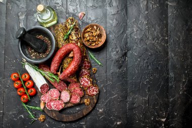 Aromatik baharat ile füme salam farklı türleri. Rustik siyah arka plan üzerine.