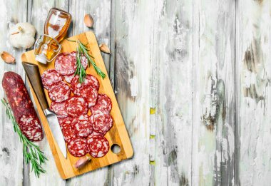 Füme salam sarımsak ve otlar ile dilimlenmiş. Rustik bir arka plan üzerinde.