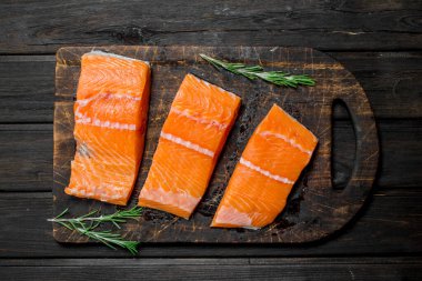 Biberiye ile çiğ somon balık fileto. Ahşap bir arka plan üzerinde.