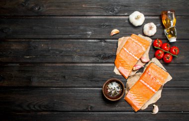 Çiğ somon balık biftek sarımsak ve domates ile. Ahşap bir arka plan üzerinde.