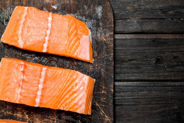 Eski bir kesme tahtasında çiğ somon balığı filetosu. Ahşap bir arka plan üzerinde