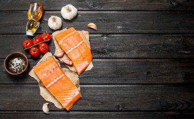 Çiğ somon balık biftek sarımsak ve domates ile. Ahşap bir arka plan üzerinde.