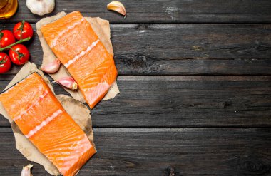 Çiğ somon balık biftek sarımsak ve domates ile. Ahşap bir arka plan üzerinde.