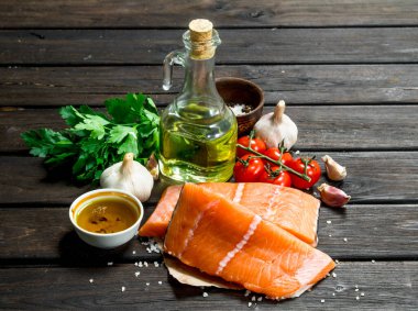 Çiğ somon balık biftek sarımsak ve domates ile. Ahşap bir arka plan üzerinde.