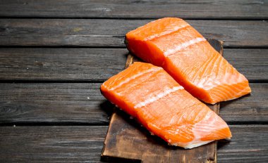 Eski bir kesme tahtasında çiğ somon balığı filetosu. Ahşap bir arka plan üzerinde