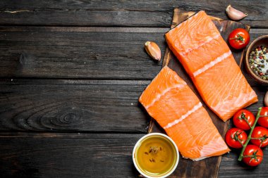 Çiğ somon fileto domates ve baharat ile balık. Ahşap bir arka plan üzerinde.