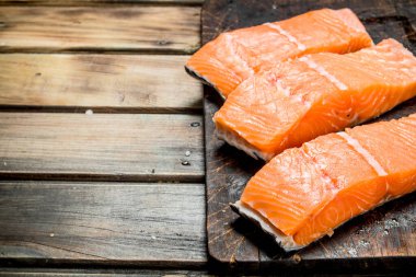 Eski bir kesme tahtasında çiğ somon balığı filetosu. Ahşap bir arka plan üzerinde