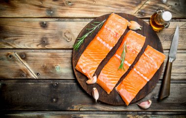 Biberiye dalları ile kesme Kurulu çiğ somon biftek. Ahşap bir arka plan üzerinde.