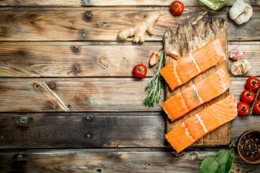 Çiğ somon fileto domates ve baharat ile balık. Ahşap bir arka plan üzerinde.