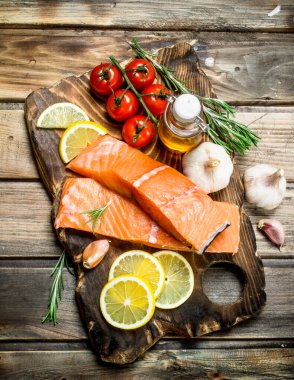 Çiğ somon fileto limon, domates ve otlar ile balık. Ahşap bir arka plan üzerinde.