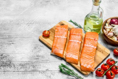 Bir kesme tahtası üzerinde domates Çiğ somon biftek. Rustik bir arka plan üzerinde.