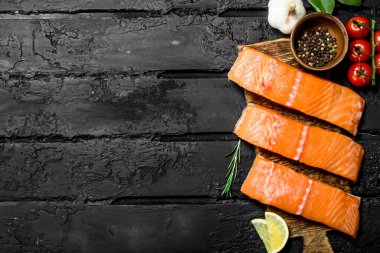 Çiğ somon fileto baharat ve otlar ile balık. Rustik siyah arka plan üzerine.