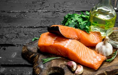 Çiğ somon balık biftek otlar ve baharatlar ile. Rustik siyah arka plan üzerine.