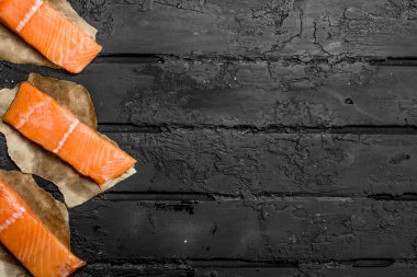 Çiğ somon biftek kağıt üzerinde balık. Rustik siyah arka plan üzerine.