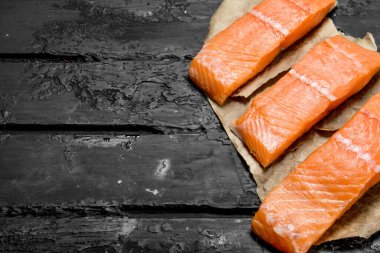 Çiğ somon biftek kağıt üzerinde balık. Rustik siyah arka plan üzerine.