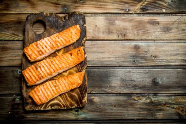 Bir kesme tahtası üzerinde ızgara somon fileto. Ahşap bir arka plan üzerinde.