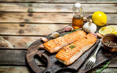 Biftek bir kesme Tahtası üzerinde limon ve baharat ile somon ızgara. Ahşap bir arka plan üzerinde.