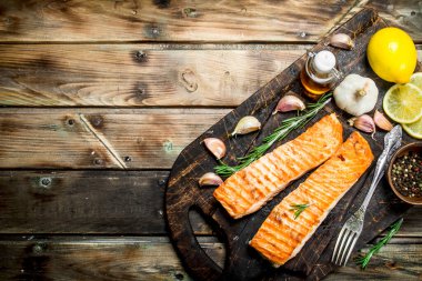 Biftek bir kesme Tahtası üzerinde limon ve baharat ile somon ızgara. Ahşap bir arka plan üzerinde.