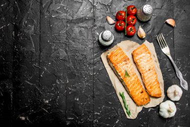 Baharat ve domates ile biftek ızgara somon. Siyah bir rustik arka planda.