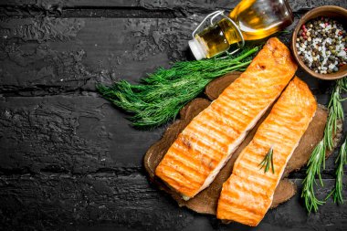 Baharat ve dereotu dalları ile ızgara somon fileto. Siyah bir rustik arka planda.