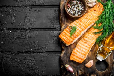 Baharat ve dereotu dalları ile ızgara somon fileto. Siyah bir rustik arka planda.