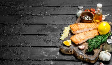 Baharat, ot ve taze dereotu dalları ile ızgara somon fileto. Siyah bir rustik arka planda.