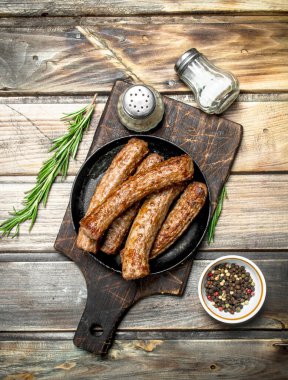 Baharat ve otlar ile sosis ızgara. Ahşap bir arka plan üzerinde.