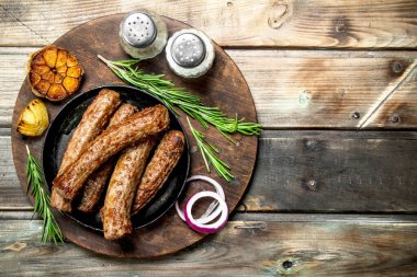 Baharat ve otlar ile sosis ızgara. Ahşap bir arka plan üzerinde.