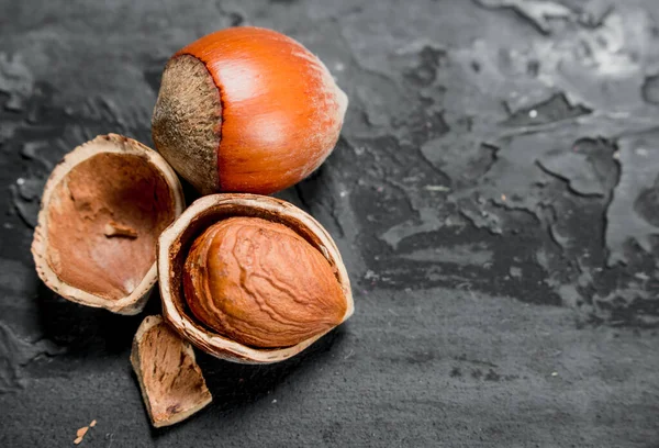 stock image Hazelnuts in the shell . On black rustic background.