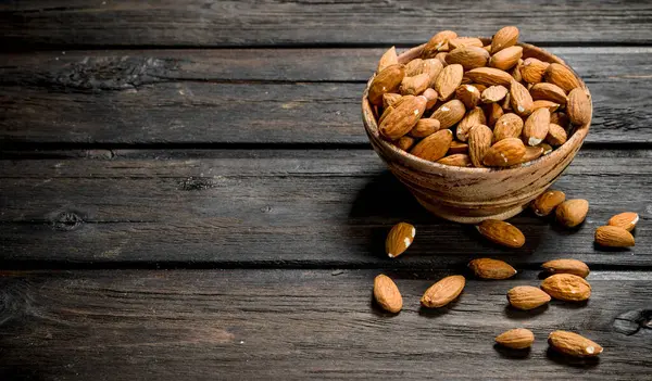 stock image Almonds in bowl . On a wooden background.