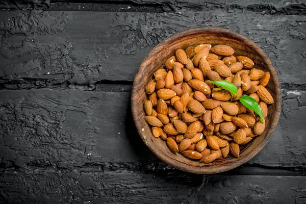 stock image Almonds in bowl. On black rustic background.