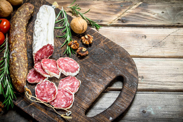 Salami with herbs and spices. On a wooden background.