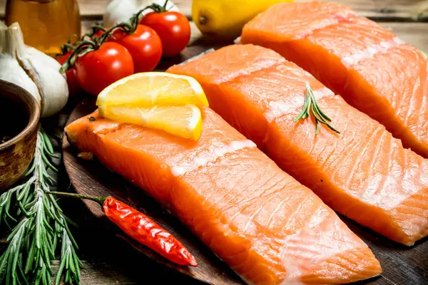 生鮭は レモン トマト ハーブ添えフィレを魚します 木製の背景に — ストック写真