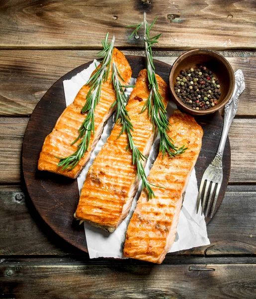 stock image Grilled salmon fillet with spices and rosemary. On a wooden background.