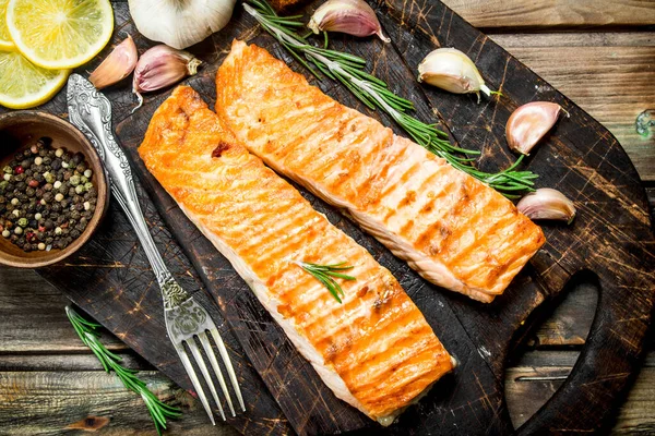 stock image Steaks grilled salmon with lemon and spices on a cutting Board. On a wooden background.