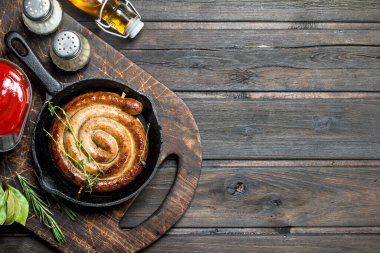 Kızarmış sosis sosu ve aromatik otlar ile. Ahşap bir arka plan üzerinde.