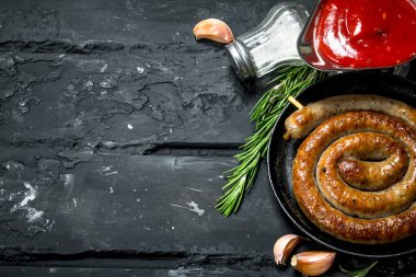 Kızarmış sosis sosu ve baharatlar ile. Rustik siyah arka plan üzerine.