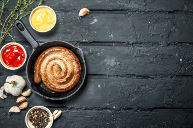 Baharat ve soslar ile kızarmış sosis. Rustik siyah arka plan üzerine.