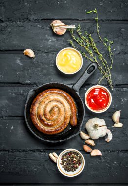 Baharat ve soslar ile kızarmış sosis. Rustik siyah arka plan üzerine.