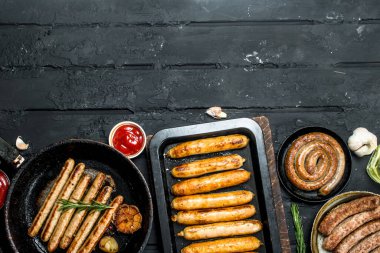 Kızarmış sosis farklı türde ürün yelpazesine. Rustik siyah arka plan üzerine.