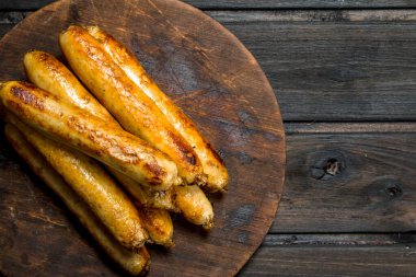 Yuvarlak bir tahta üzerinde Dana sosis ızgara. Ahşap bir arka plan üzerinde.