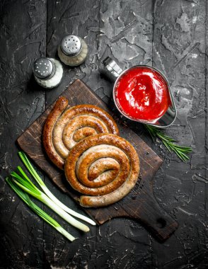 Izgara sosis domates sosu ve baharatlar ile. Ahşap bir arka plan üzerinde.