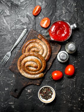 Izgara sosis domates sosu ve baharatlar ile. Ahşap bir arka plan üzerinde.