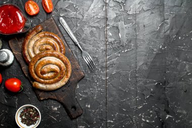 Izgara sosis domates sosu ve baharatlar ile. Ahşap bir arka plan üzerinde.