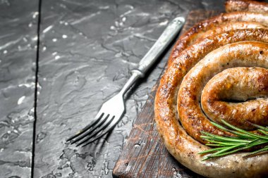 Baharat ile sosis ızgara. Rustik siyah arka plan üzerine.