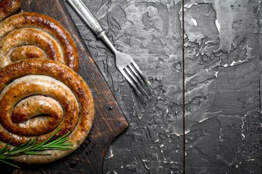 Baharat ile sosis ızgara. Rustik siyah arka plan üzerine.