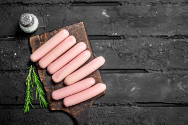 Rosemary ile sosis haşlama. Rustik siyah arka plan üzerine.