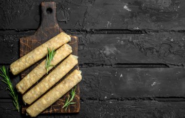 Baharat ve otlar ile çiğ sosis. Rustik siyah arka plan üzerine.