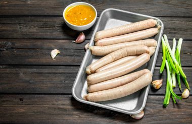 Çiğ sosis sosu ve yeşil soğan ile Pan. Ahşap bir arka plan üzerinde.